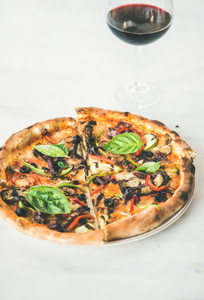 Freshly baked pizza with vegetables basil and glass of wine