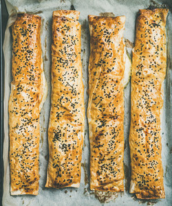 Flat lay of freshly baked Turkish borek pastry rolls with spinach