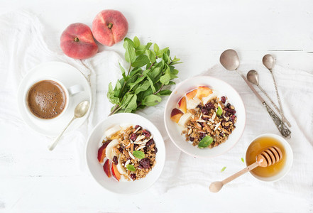 Healthy breakfast Bowl of oat granola with yogurt fresh fruit mint and honey Coffee vintage silverware Top view