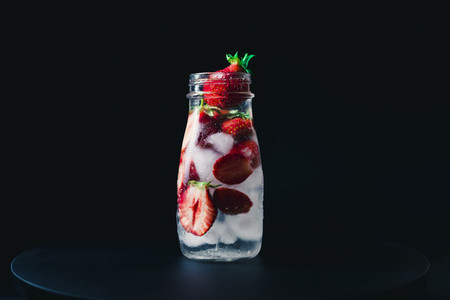 strawberry infused water with ice on a black background