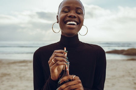 Woman smiling with cola at the beach