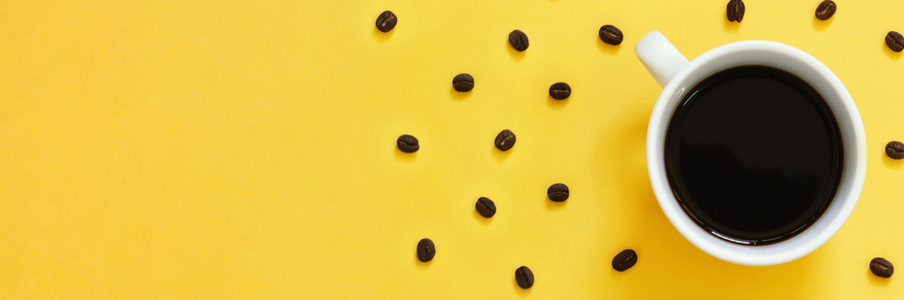 Top view of black coffee and coffee beans on yellow background