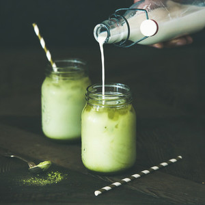 Refreshing iced coconut matcha latte in glass jars  copy space