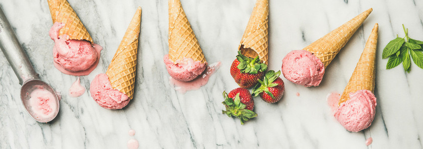 Flat lay of homemade yogurt strawberry ice cream in waffle cones