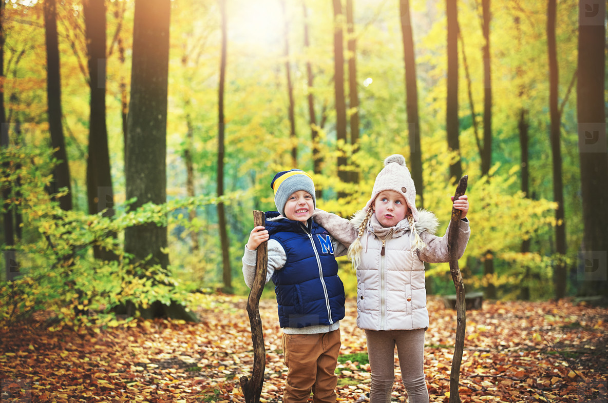 Two kids holding branches in autumn forest