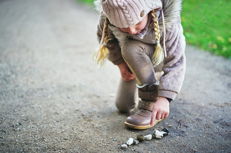 Little girl touches stones on a road