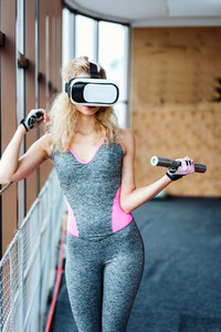 Beautiful girl in the gym with VR headset