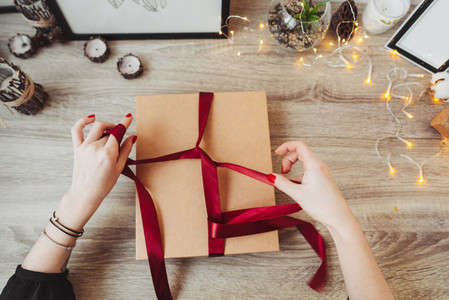 Woman wrapping present in paper with red ribbon