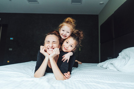 Mom and two daughters have fun on the bed