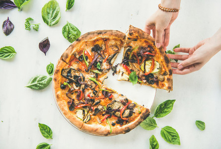 Womans hands taking Freshly baked vegetarian pizza over marble background