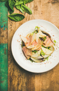 Fresh salad with smoked turkey ham and pear  rustic background