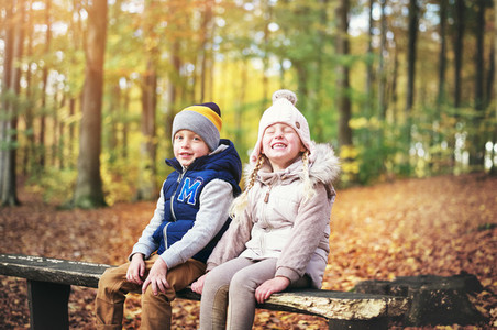 Two laughing kids sitting on a bench