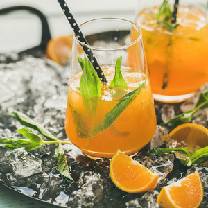 Refreshing cold alcoholic summer cocktail with orange  peppermint and ice