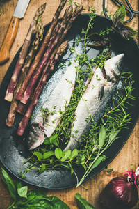 Raw uncooked sea bass fish with herbs and vegetables