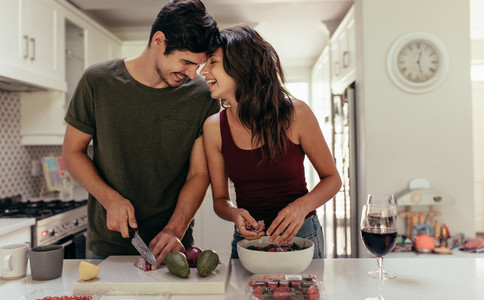 Loving couple cutting vegetables together in kitchen