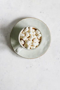 Hot chocolate with marshmallow in a ceramic mug over textured white background  Minimalist style  top view  copy space