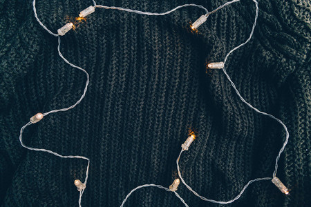 Festoon lights on a warm sweater Top view winter or autumn flat lay