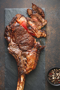 Top view of grilled marble beef steak Tomahawk on black slate  Flat lay  dinner concept