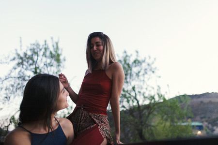 Two young women watch the sunset from their balcony