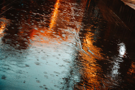 Abstract photography of rain  Raindrops on asphalt in the light of evening lights