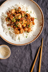 Top view on sesame chicken pieces with rice on a ceramic plate  Chinese traditional dish  Copy space