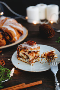 Piece of Swedish tea ring Christmas cake with cinnamon  pecans and raisins on a warm knitted sweater  The concept of cozy winter Holidays and homemade bakery