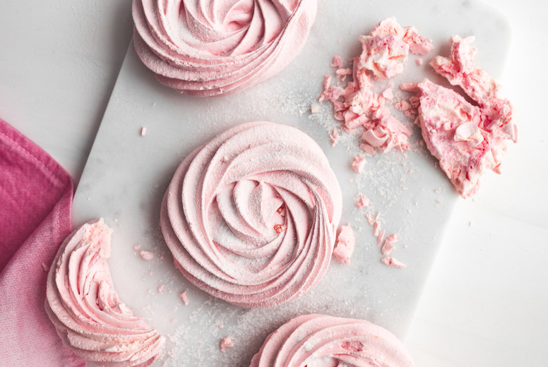 Top view of pink meringue on a white marble tray. Flat lay composition.