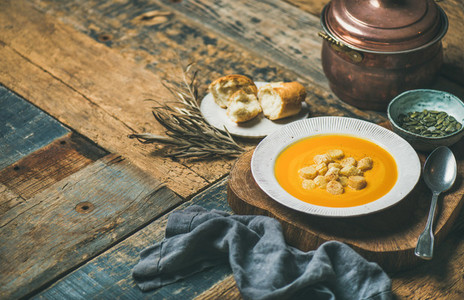 Warming pumpkin cream soup with croutons and seeds  wooden background