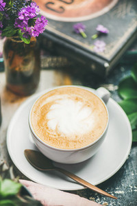 Classic foamy cappuccino coffee in cup with flowers  selective focus