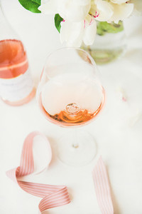 Rose wine in glass and bottle pink ribbon peony flowers