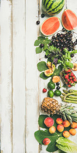 Seasonal fruit  vegetables and greens over wooden background  vertical composition
