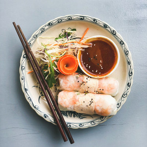 Asian style dinner  Flat lay of steamed dumplings Dim sum and summer rice paper rolls with shrimp and sauce over blue table  top view  copy space  Chinese cuisine