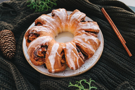Swedish tea ring Christmas cake with cinnamon pecans and raisins on a warm knitted sweater The concept of cozy winter Holidays and homemade bakery