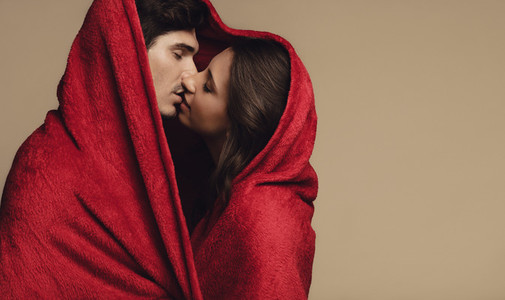 Loving couple kissing under a blanket