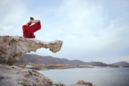 Young brunette woman dancing above a rock near sea coast
