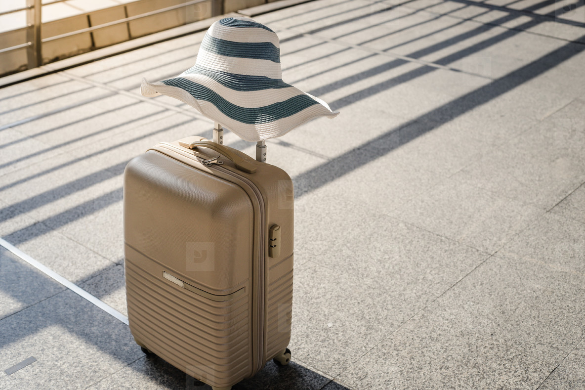A suitcase with summer hat at airport departure