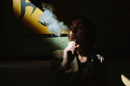 girl sits and smokes electronic cigarette