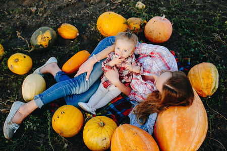 mother and daughter lie between pumpkins