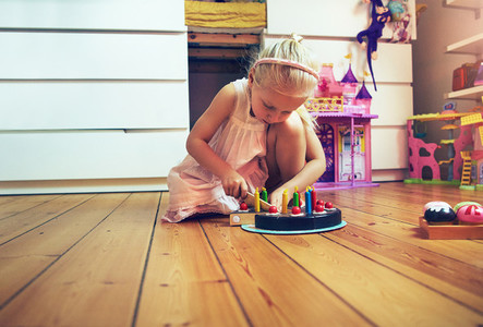 Girl slicing toy cake on the floor