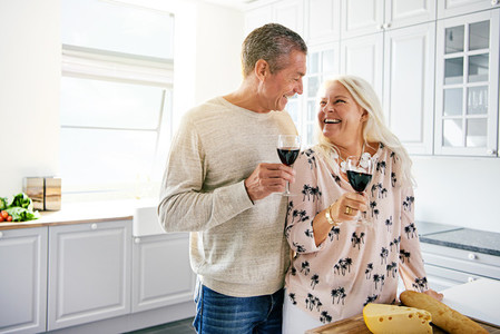 Laughing retired couple drinking a glass of wine