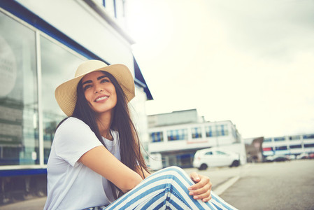Woman with whimsical smile seated on curb