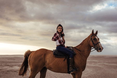 Woman horse riding on beach in evening
