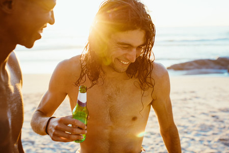 Two young men with beer at beach
