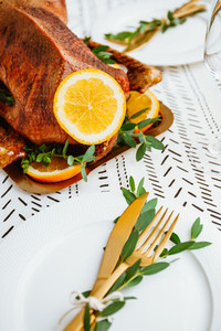 Festive table setting with whole roasted goose on a golden tray for celebrate event or Christmas family dinner