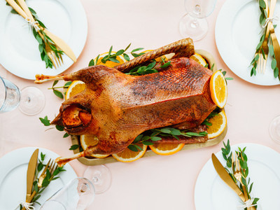 Festive table setting with whole roasted goose on a golden tray for celebrate event or Christmas family dinner  Top view  flat lay
