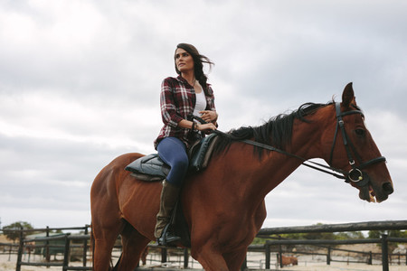 Woman riding her horse in corral