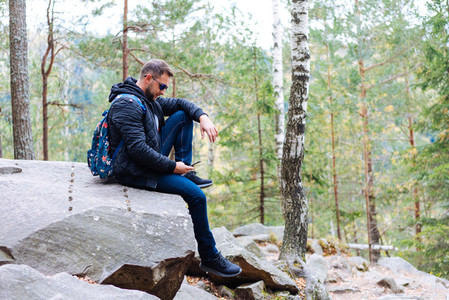 guy sits in the woods on a rock