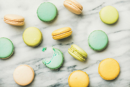 Colorful French macaroons over grey marble background top view