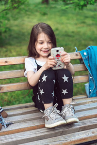 little girl with a smartphone sitting on a bench