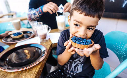 small boy eating dessert with blueberries